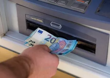 Standing next to an ATM  and handling money
