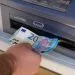 Standing next to an ATM  and handling money
