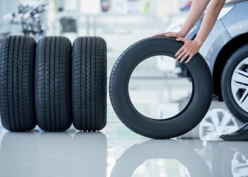 4 new tires that change tires in the auto repair service center, blurred background, the background is a new car in the stock blur for the industry, a four-wheeled tire set at a large warehouse