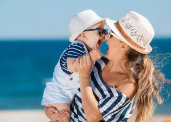 Happy family relaxing by the sea. Happy family resting at beach in summer. mother with baby boy resting on the beach. Young mother and her adorable little daughter on beach vacation