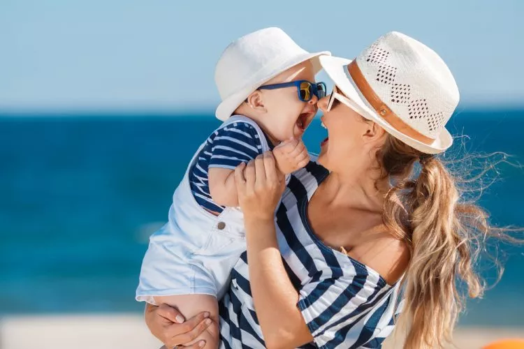Happy family relaxing by the sea. Happy family resting at beach in summer. mother with baby boy resting on the beach. Young mother and her adorable little daughter on beach vacation