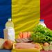 complete national flag of romania covers whole frame, waved, crunched and very natural looking. In front plan are fundamental food ingredients for consumers, symbolizing consumerism an human needs