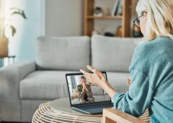Military woman in video call with psychologist for mental health problem, anxiety and trauma with laptop screen virtual technology. Soldier or veteran consulting with psychology therapy in zoom call.