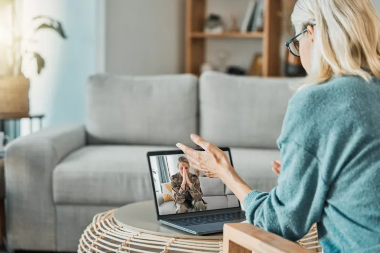 Military woman in video call with psychologist for mental health problem, anxiety and trauma with laptop screen virtual technology. Soldier or veteran consulting with psychology therapy in zoom call.